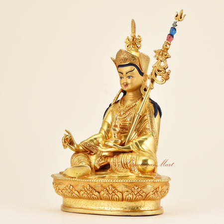 Left-side view of Buddhist Guru Padmasambhava statue, gold gilded handmade sacred art highlighting detailed robes and traditional craftsmanship.
