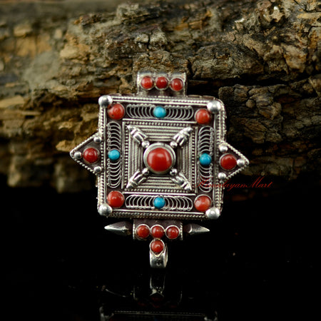 Handmade Buddhist silver pendant with coral and turquoise gemstone inlay, crafted in traditional Tibetan style.