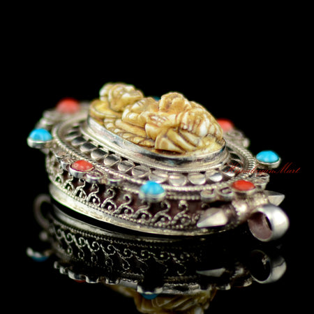 Left view of Dzambhala Wealth Deity Pendant highlighting intricate siko filigree carving in silver.