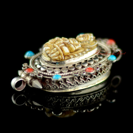 Right view of Dzambhala Wealth Deity Pendant showing silver ghau design with coral and turquoise details.