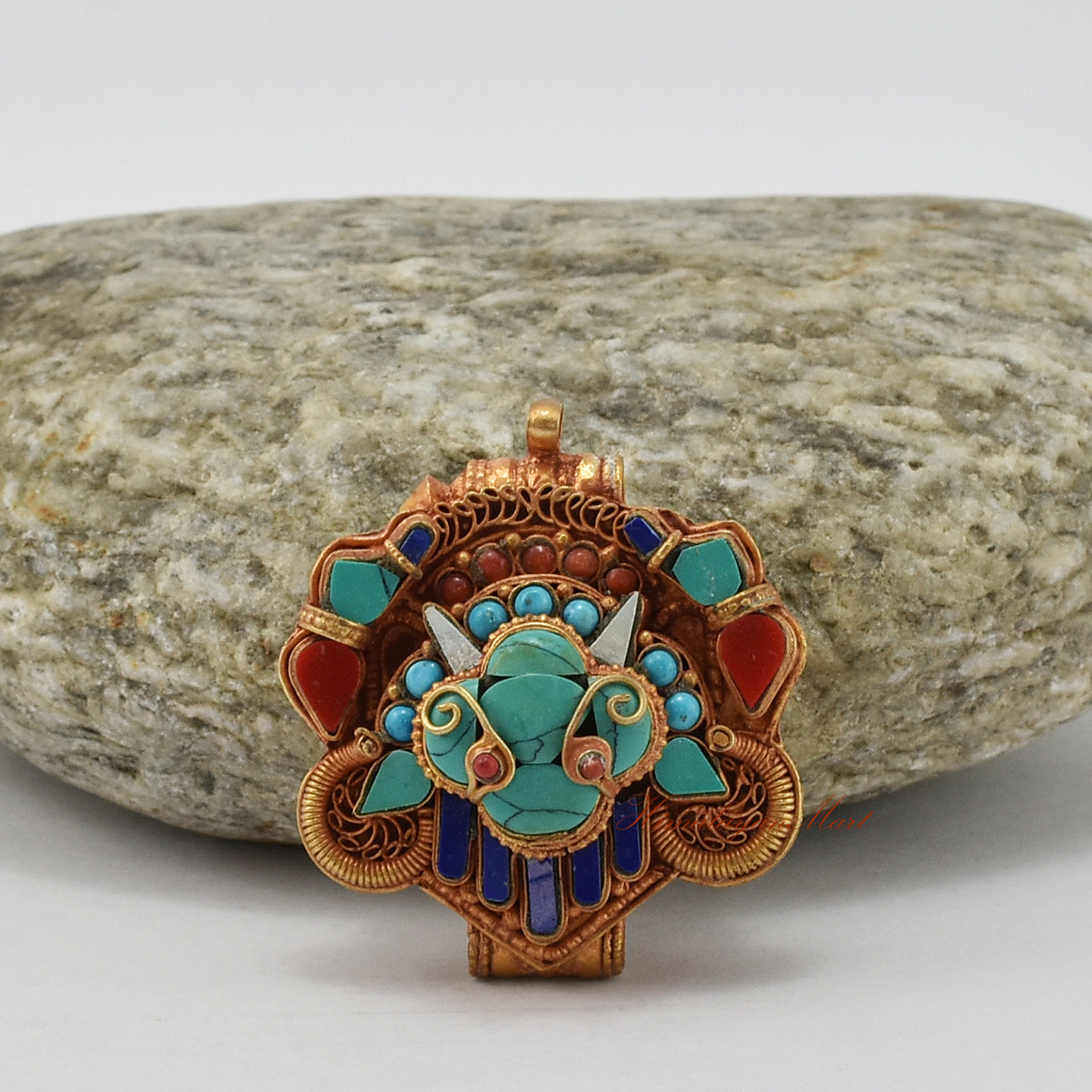 Top-down view of handcrafted Chhepu Face Ghau prayer box pendant, showing detailed carvings and gemstone decorations.