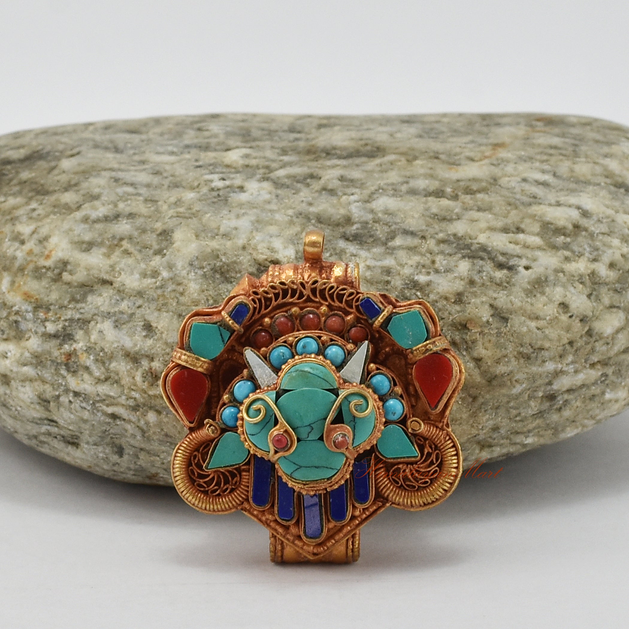 Top-down view of handcrafted Chhepu Face Ghau prayer box pendant, showing detailed carvings and gemstone decorations.