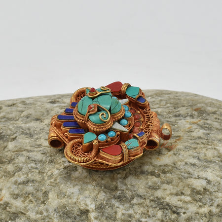 Alternative left-angle view of handcrafted Chhepu Face Ghau pendant, highlighting detailed carvings and gemstone inlay.