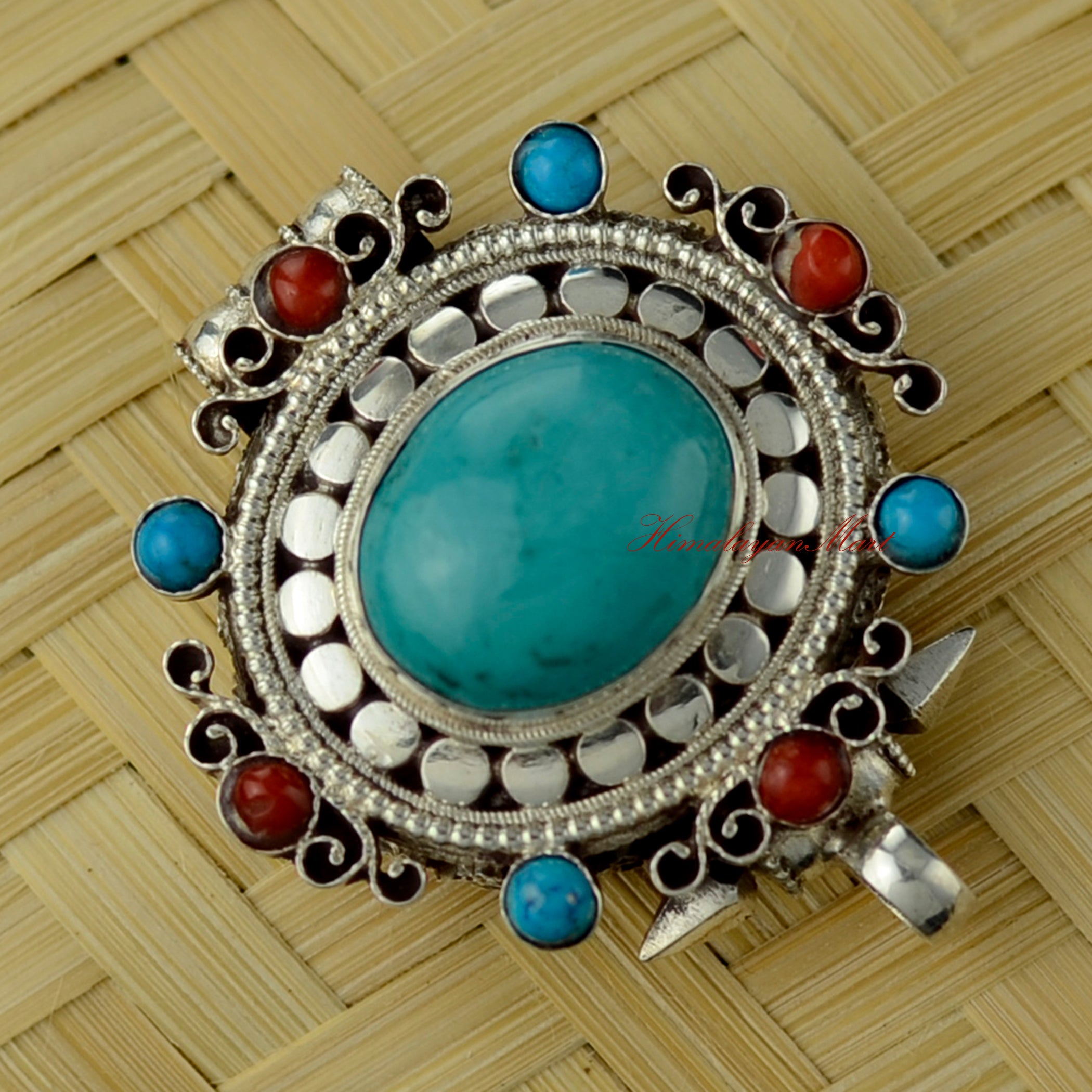Angled right-down view of Himalayan Pendant Jewelry highlighting siko filigree and turquoise stone setting.