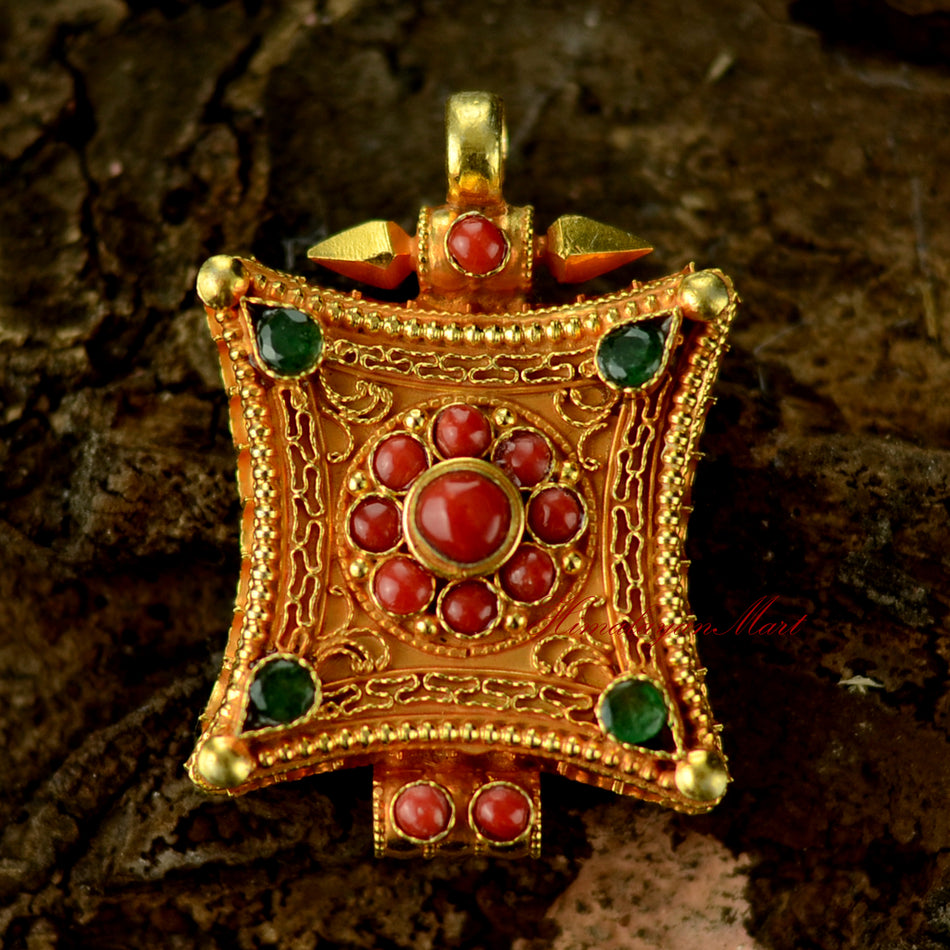 Handcrafted Tibetan gemstone pendant in silver with intricate filigree and coral and emerald gemstones.